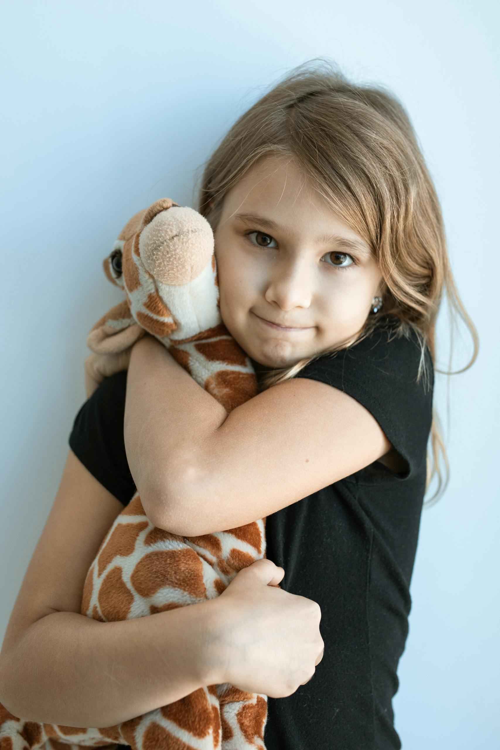 Young girl hugging giraffe plush toy, capturing innocence and joy.